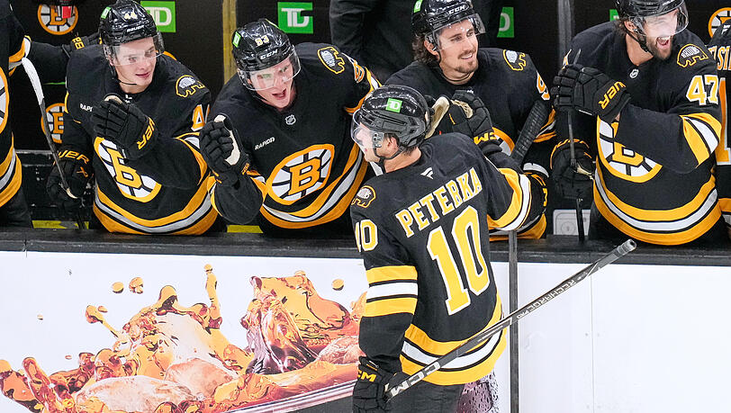 JJ Peterka holt sich nach seinem ersten Tor für die Boston Bruins an der Bande seine Glückwünsche ab. JJ Peterka holt sich nach seinem ersten Tor für die Boston Bruins an der Bande seine Glückwünsche ab.
