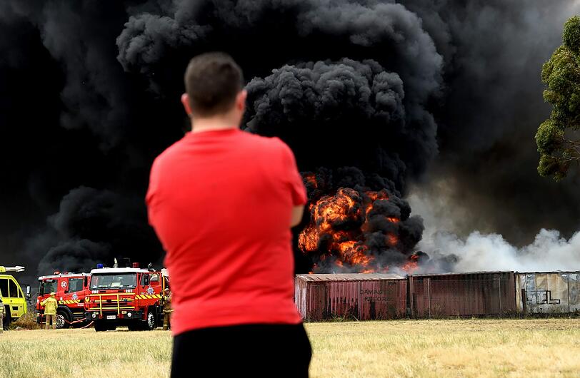 Ein Mann beobachtet die Löscharbeiten der Feuerwehr in Brisbane. Diese kämpft gegen einen Brand und beißenden Rauch, den brennende Autoreifen ausgelöst haben. Das Feuer war weithin sichtbar.