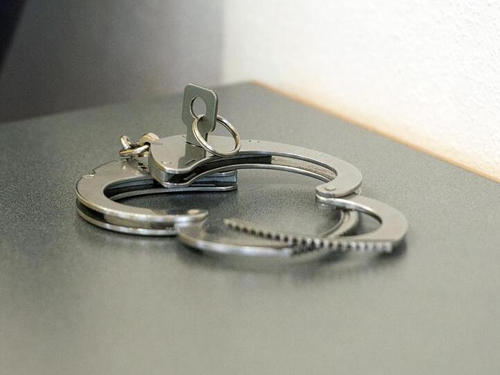 Handschellen liegen auf einem Tisch. Foto: Armin Weigel/dpa/Illustration