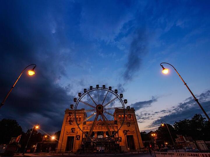 Ein Riesenrad steht am späten Abend auf dem Königsplatz vor der Kulisse der Propyläen. Foto: Peter Kneffel/dpa/Archivbild