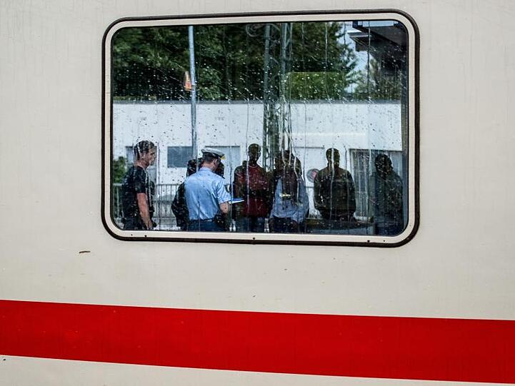 Zwei Bundespolizisten nehmen auf einem Bahnhof in Bayern die Personalien von im Zug aufgegriffenen Flüchtlingen auf.