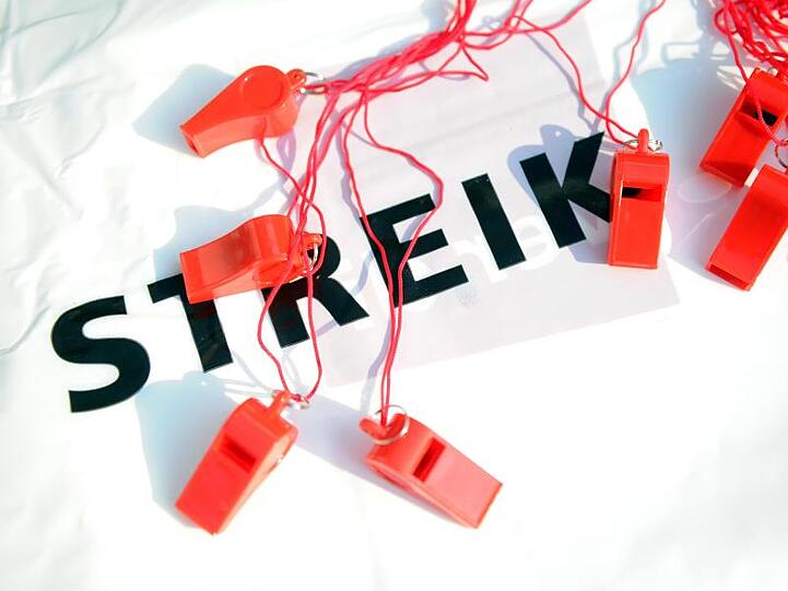 Trillerpfeifen liegen vor einer Kundgebung auf einem Tisch mit der Aufschrift "Streik". Foto: Caroline Seidel/Archivbild