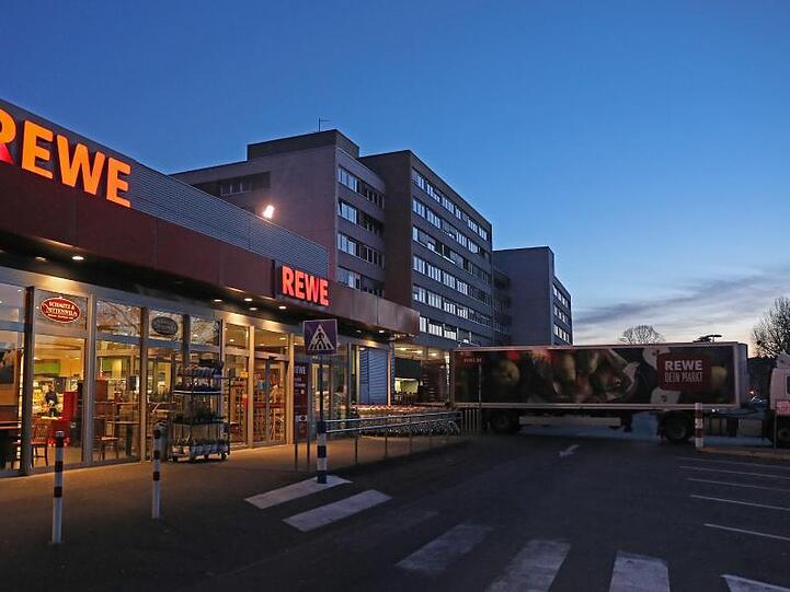 Ein Lkw steht am frühen Morgen vor einem Rewe Supermarkt, der mit Waren beliefert wird.