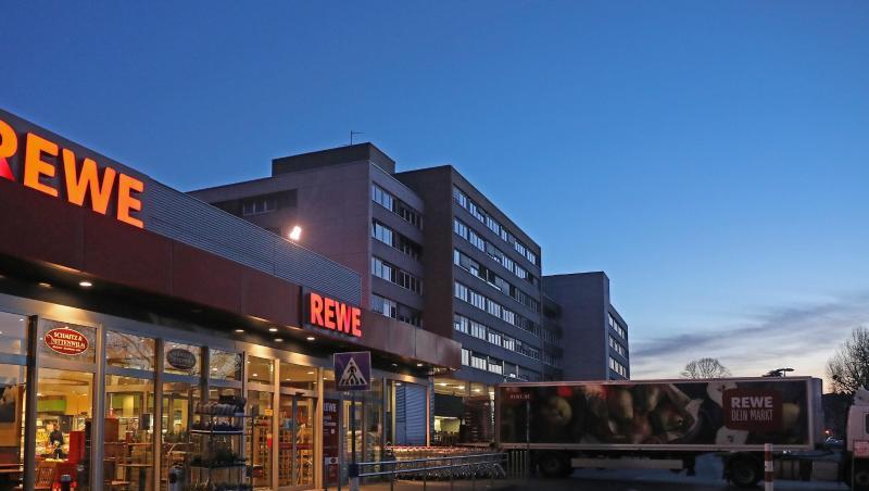 Ein Lkw steht am frühen Morgen vor einem Rewe Supermarkt, der mit Waren beliefert wird.