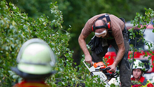 Feuerwehrleute zersägen einen durch ein Unwetter umgestürzten Baum. Feuerwehrleute zersägen einen durch ein Unwetter umgestürzten Baum.