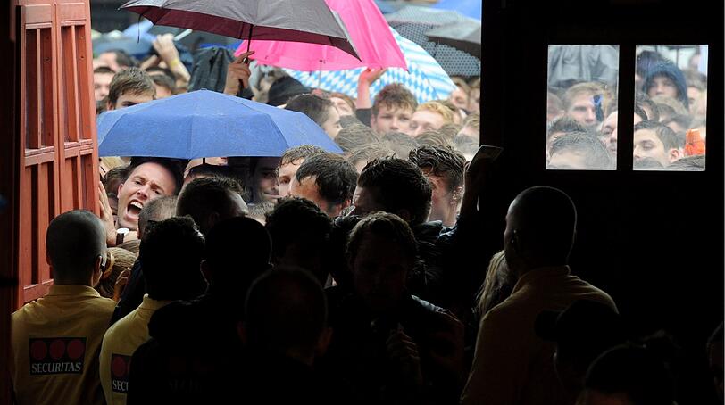 Trotz Sauwetter und Regen warten bereits viele Wiesngänger auf den Wiesnanstich. Der Kampf um den Platz im Bierzelt beginnt schon am frühen Morgen. Die ersten Bilder.