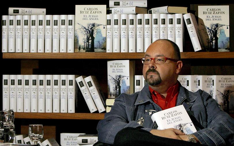 Der spanische Bestseller-Autor Carlos Ruiz Zafon sitzt vor einer Bücherwand. Zafon ist im Alter von 55 Jahren in Los Angeles gestorben. Er sei an Krebs erkrankt gewesen, meldete die Nachrichtenagentur Europapress unter Berufung auf seinen Verlag Planeta am 19.06.2020. (Archivbild)