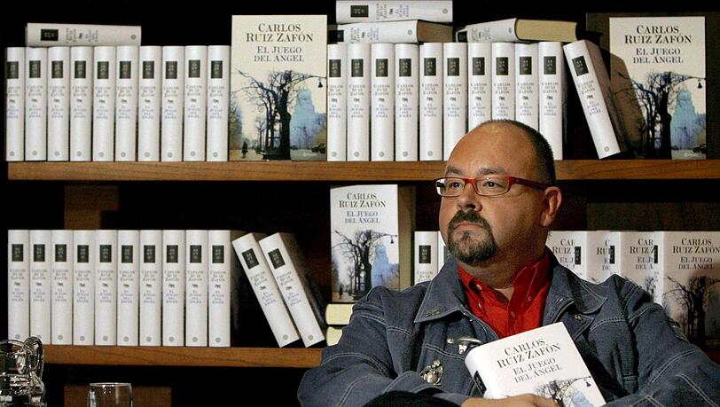 Der spanische Bestseller-Autor Carlos Ruiz Zafon sitzt vor einer Bücherwand. Zafon ist im Alter von 55 Jahren in Los Angeles gestorben. Er sei an Krebs erkrankt gewesen, meldete die Nachrichtenagentur Europapress unter Berufung auf seinen Verlag Planeta am 19.06.2020. (Archivbild) Der spanische Bestseller-Autor Carlos Ruiz Zafon sitzt vor einer Bücherwand. Zafon ist im Alter von 55 Jahren in Los Angeles gestorben. Er sei an Krebs erkrankt gewesen, meldete die Nachrichtenagentur Europapress unter Berufung auf seinen Verlag Planeta am 19.06.2020. (Archivbild)