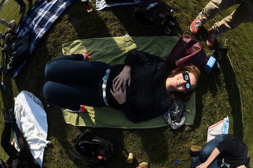 Diese junge Dame hat es sich im Englischen Garten gemütlich gemacht und sieht sich die Sonnenfinsternis von einer Decke aus an.