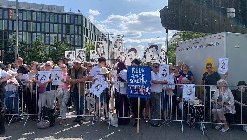 &bdquo;Omas gegen Rechts&ldquo; stehen w&auml;hrend des Gedenkaktes mit Plakaten unter den Zuh&ouml;reren.