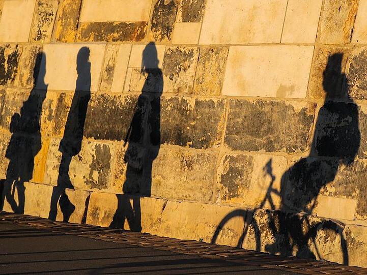 Die Schatten von Spaziergängern an einer Ufermauer an der Elbe in Dresden. Ein Hauch von Frühling weht derzeit durch fast ganz Deutschland.