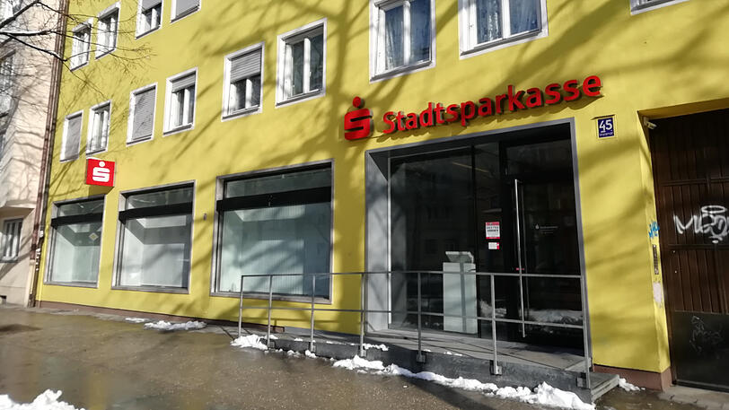 Implerstrasse 45: Das Gelb des Gebäudes strahlt mit der Münchner Wintersonne um die Wette, doch der Schein trügt. Die herabgelassenen Jalousien werfen lange Schatten durch den leergefegten Raum. Die Sparkasse ist hier allerdings nicht mehr Mieter, wie es weiter geht, bleibt unklar.