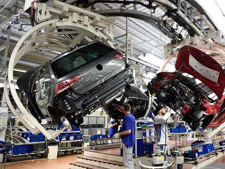 Mitarbeiter arbeiten im Volkswagen-Werk an einer Fertigungsstrecke des VW Golf 7. Foto: Rainer Jensen/Archivbild