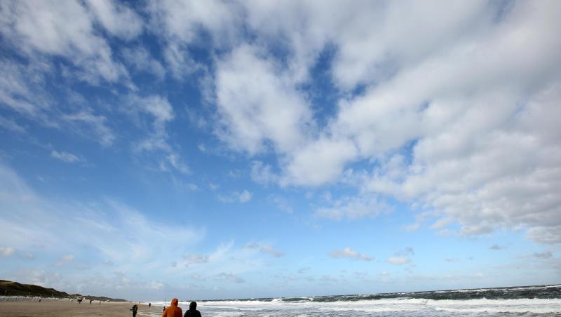 Bei windigem Wetter sind Spaziergänger am Strand von Westerland auf Sylt unterwegs.