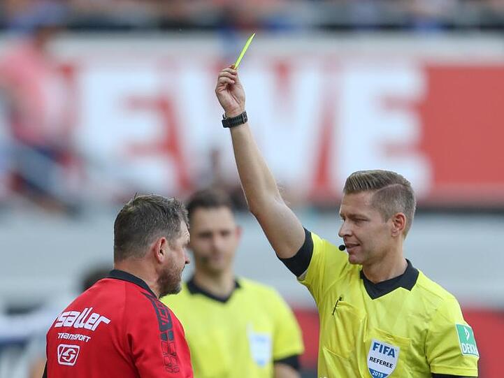 Schiedsrichter Tobias Welz (r) zeigt Paderborn-Trainer Baumgart (l) die erste Gelbe Karte.
