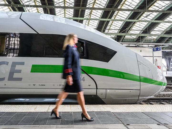 Eine Mitarbeiterin der Bahn geht an einem ICE mit dem neuen Design vorbei.