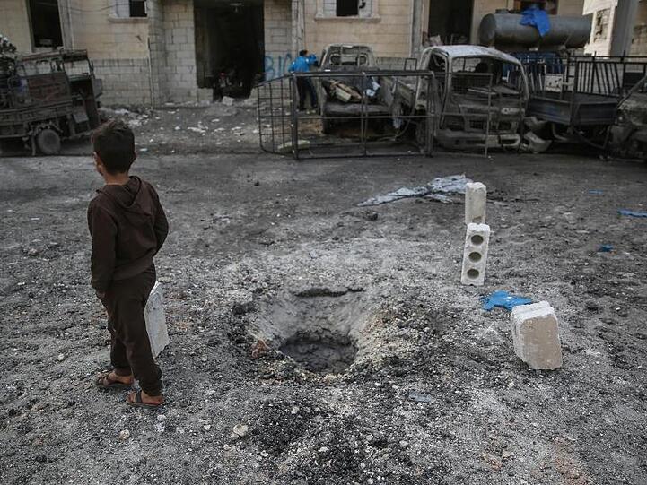 Ein syrisches Kind geht an einem Loch im Boden vorbei, das sich nach einem Raketenbeschuss gebildet hat, der Berichten zufolge von den syrischen Regierungstruppen durchgeführt wurde und mehrere Tote und eine große Zahl von Verwundeten zur Folge hatte.