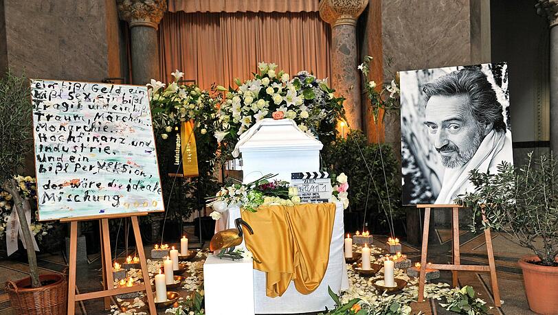 Der mit weißen Lilien geschmückte Sarg und der geliebte Olivenbaum von Regisseur Helmut Dietl stehen bei seiner Trauerfeier in der Aussegnungshalle am Nordfriedhof in München. Der mit weißen Lilien geschmückte Sarg und der geliebte Olivenbaum von Regisseur Helmut Dietl stehen bei seiner Trauerfeier in der Aussegnungshalle am Nordfriedhof in München.