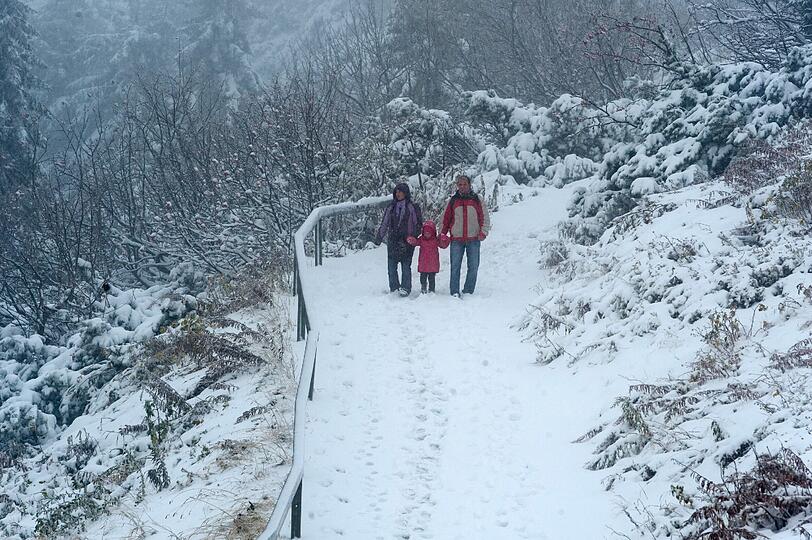 Eine Familie wandert am Samstag unterhalb des Gipfels am 1456 Meter hohen Großen Arber (Niederbayern) auf einem mit Schnee bedeckten Weg.