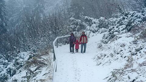 Eine Familie wandert am Samstag unterhalb des Gipfels am 1456 Meter hohen Großen Arber (Niederbayern) auf einem mit Schnee bedeckten Weg.