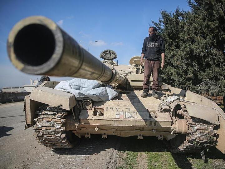 Ein Kämpfer der Nationalen Befreiungsfront (NFL) steht auf einem Panzer der syrischen Regierungstruppen.