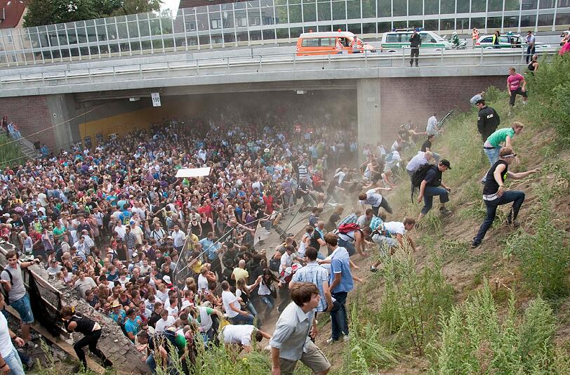 Teilnehmer der Loveparade 2010 durchbrechen auf dem Loveparade-Gelaende am ehemaligen Gueterbahnhof in Duisburg nach einer Massenpanik mit Toten Absperrgitter