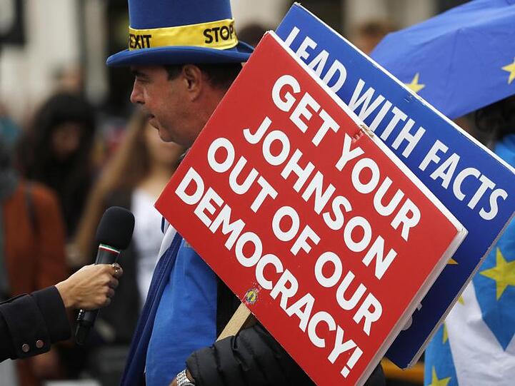 Ein Brexit-Gegner spricht vor dem Parlament zu Journalisten und hält ein Schild mit der Aufschrift "Get your Johnson out of our democracy" (Entfernt euren Johnson aus unserer Demokratie).