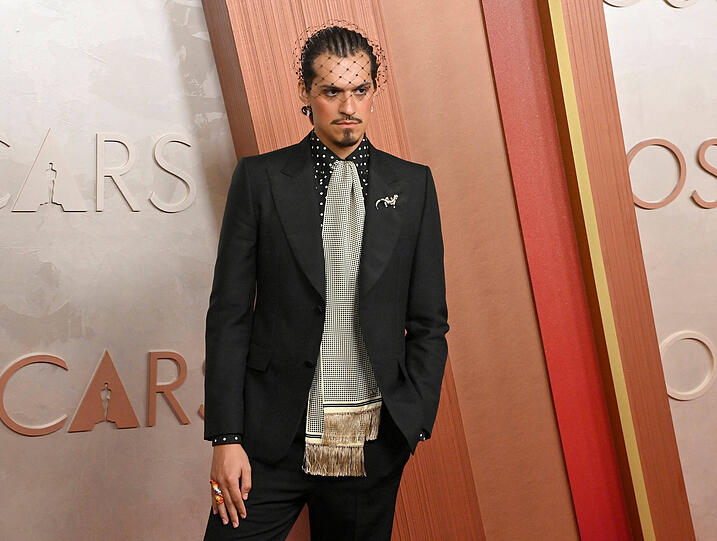 Omar Apollo fällt mit dem Look von Valentino definitiv auf. Der Designer Alessandro Michele hat die Fliege durch einen Schal ersetzt. Der Stylist des Sängers hat noch einen Schleier auf den Kopf gesetzt. Und Omar hat den Schmucktrend Brosche noch am Revers. Eines der drei Accessoires ist für mich definitiv zu viel. Aber er sieht natürlich fantastisch aus und zeigt auch, dass Männer rosiges Rouge und schwarzen Eyeliner tragen können. Omar schenkt uns definitiv den ultimativen Schleier Moment der Oscars.