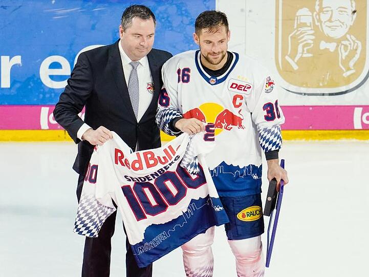 Münchens Yannic Seidenberg (r) und Christian Winkler halten ein Trikot mit der Aufschrift &bdquo;1000&ldquo;. Foto: Uwe Anspach/dpa