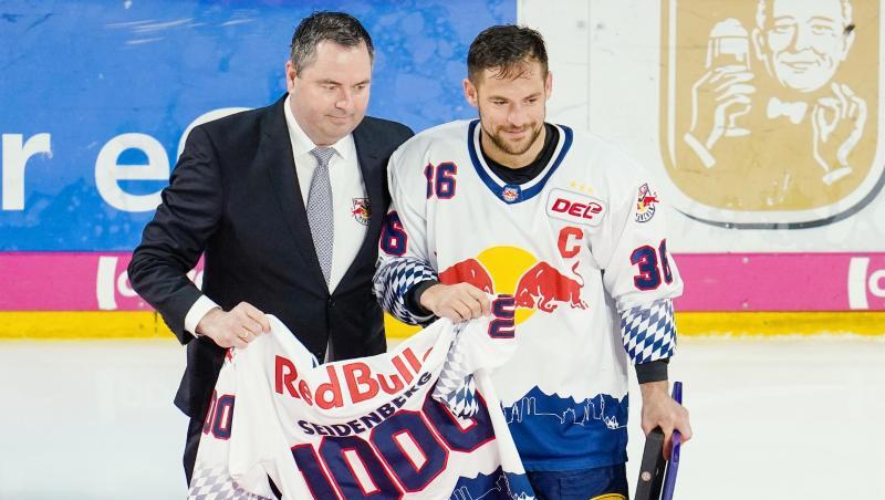 Münchens Yannic Seidenberg (r) und Christian Winkler halten ein Trikot mit der Aufschrift „1000“. Foto: Uwe Anspach/dpa Münchens Yannic Seidenberg (r) und Christian Winkler halten ein Trikot mit der Aufschrift „1000“. Foto: Uwe Anspach/dpa