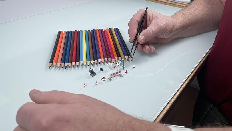 Präzise werden die einzelnen Gegenstände mit einer Pinzette ausgerichtet.