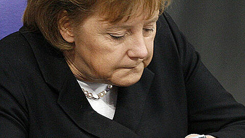 Angela Merkel blickt auf ihr Handy