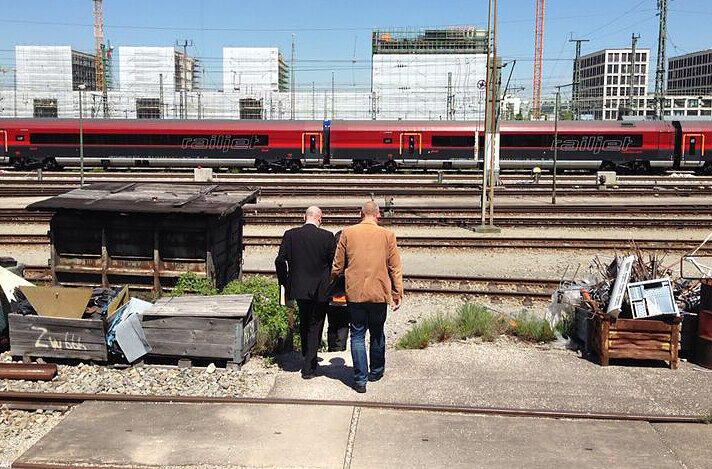 Ein Bahnarbeiter führt zwei kriminalpolizisten zum Railjet, in dem das Neugeborene getötet wurde.