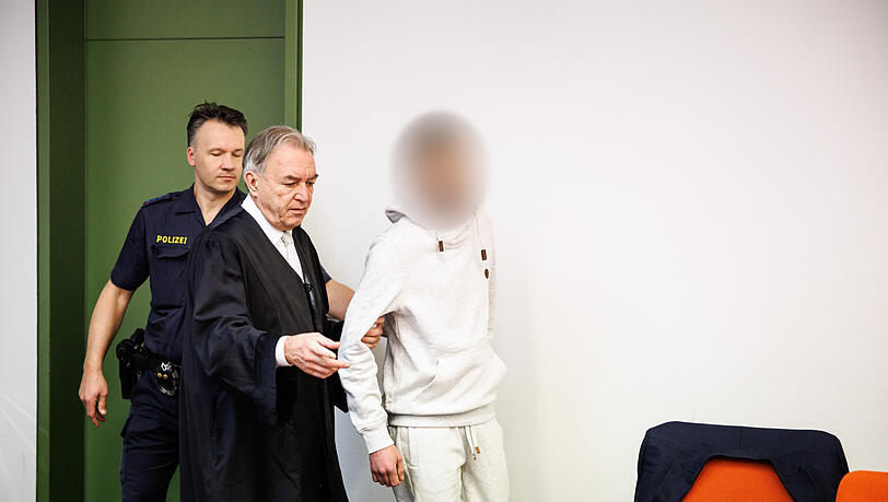 Ein wegen Totschlags angeklagter Mann (r), der seine fünf Wochen alte Tochter in Oberammergau umgebracht haben soll, wird zu Prozessbeginn in einen Gerichtssaal vom Landgericht in München geführt. In der Mitte steht sein Rechtsanwalt Sewarion Kirkitadse. Er soll das Baby geschüttelt und mit dem Kopf gegen einen harten Gegenstand geschlagen haben.