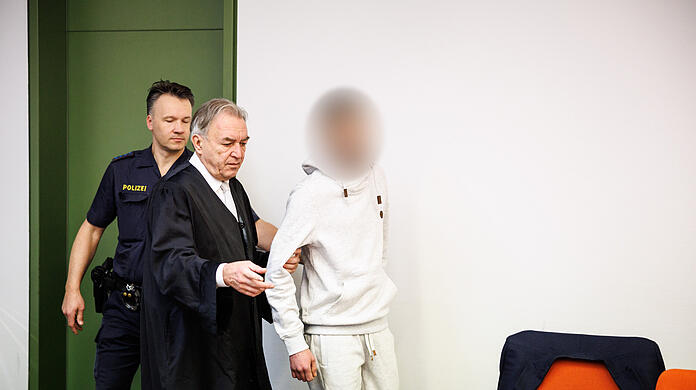 Ein wegen Totschlags angeklagter Mann (r), der seine fünf Wochen alte Tochter in Oberammergau umgebracht haben soll, wird zu Prozessbeginn in einen Gerichtssaal vom Landgericht in München geführt. In der Mitte steht sein Rechtsanwalt Sewarion Kirkitadse. Er soll das Baby geschüttelt und mit dem Kopf gegen einen harten Gegenstand geschlagen haben.
