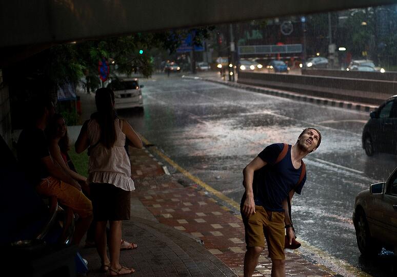 "Noch warten oder einfach loslaufen?", denkt sich dieser Tourist bei einem heftigen Platzregen-Schauer in Kuala Lumpur.