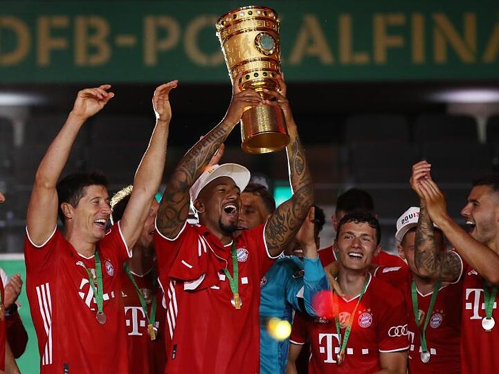 Münchens Jerome Boateng (M) hält die Trophäe nach dem Spiel hoch. Foto: Alexander Hassenstein/Getty Images Europe/Pool/dpa