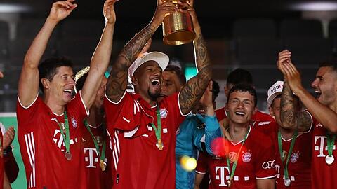 Münchens Jerome Boateng (M) hält die Trophäe nach dem Spiel hoch. Foto: Alexander Hassenstein/Getty Images Europe/Pool/dpa