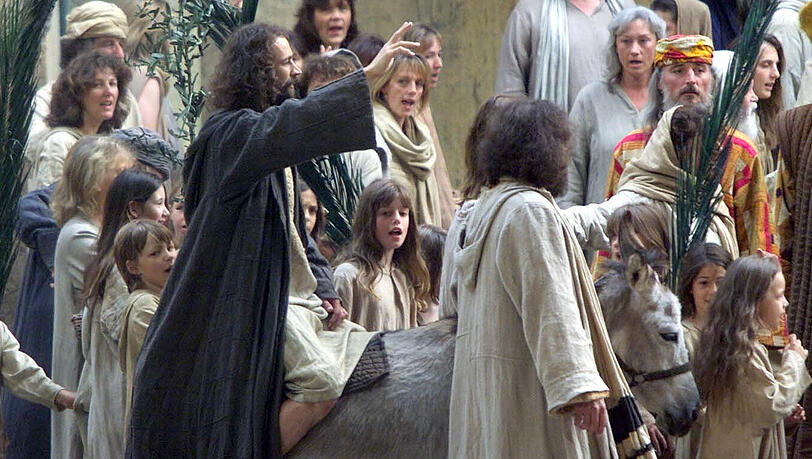 Anno 2000: Schauspieler Martin Norz sitzt während der Fotoprobe zu den Passionsspielen in Oberammergau winkend auf einem Esel. Anno 2000: Schauspieler Martin Norz sitzt während der Fotoprobe zu den Passionsspielen in Oberammergau winkend auf einem Esel.