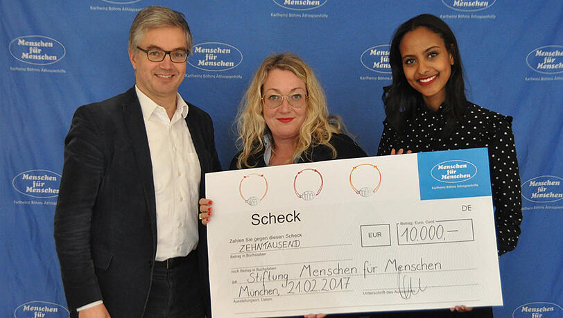 Vorstand Dr. Sebastian Brandis (l.), Schmuckdesignerin Julia Neumann (m.) und Menschen für Menschen-Botschafterin Sara Nuru (r.) bei der Scheckübergabe. Vorstand Dr. Sebastian Brandis (l.), Schmuckdesignerin Julia Neumann (m.) und Menschen für Menschen-Botschafterin Sara Nuru (r.) bei der Scheckübergabe.