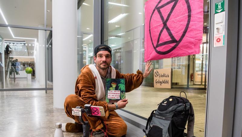 Extinction-Rebellion-Aktivist Thomas Nier klebt mit der Hand an einer Scheibe der Siemens Zentrale. Foto: Matthias Balk/dpa Extinction-Rebellion-Aktivist Thomas Nier klebt mit der Hand an einer Scheibe der Siemens Zentrale. Foto: Matthias Balk/dpa