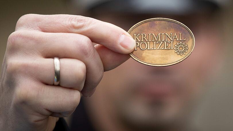 Ein Polizist hält eine Dienstmarke der Kriminalpolizei in seiner Hand. Dienstmarken, aber auch Dienstausweise, können Polizisten dadurch identifizieren, dass sie eine bestimmte Dienstnummer tragen. (Symbolbild)