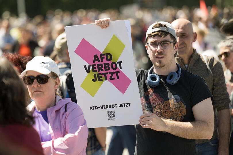 Ein Demonstrant hält ein Plakat mit der Aufschrift "AfD Verbot Jetzt".