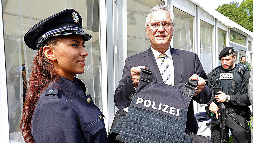 Innenminister Joachim Herrmann (CSU) präsentiert neben Bereitschaftspolizistin in Ausbildung Dinal Sebnem in Gmund eine verstärkte schusssichere Weste der Polizei.