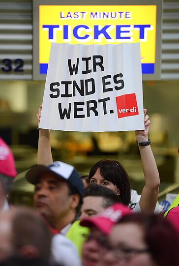 Mit einem Plakat mit der Aufschrift "Wir sind es wert" und Trillerpfeifen fordern Sicherheitsmitarbeiter am Flughafen Frankfurt mehr Lohn.