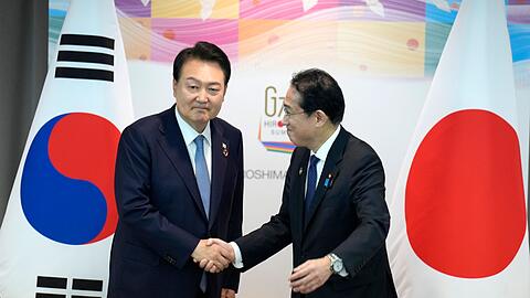 Japans Ministerpräsident Fumio Kishida und der südkoreanische Präsident Yoon Suk Yeol schütteln sich die Hände während ihres bilateralen Treffens anlässlich des G7-Gipfels.
