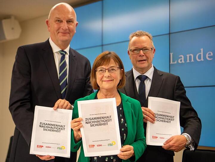Dietmar Woidke (SPD), Ministerpräsident von Brandenburg, Ursula Nonnemacher, Fraktionsvorsitzende von Bündnis 90/Die Grünen in Brandenburg, und Michael Stübgen, Landesvorsitzender von CDU Brandenburg, mit einem Exemplar des Vertrags.