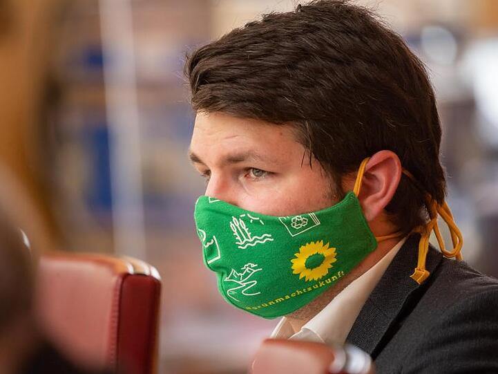 Johannes Becher (Grüne) trägt währenden der Sitzung des bayerischen Landtags einen Mundschutz. Foto: Peter Kneffel/dpa/Archivbild