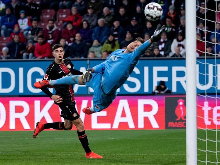 Kai Havertz (l) von Leverkusen trifft gegen Augsburgs Torwart Gregor Kobel zum 1:2. Foto: Sven Hoppe