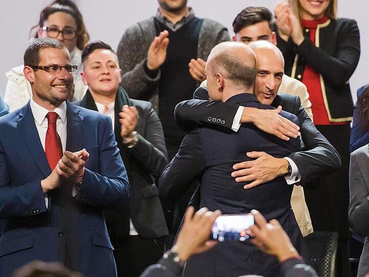 Joseph Muscat (mit dem Rücken zur Kamera) nimmt Parteimitglied Chris Fearne nach seiner Abschiedsrede in den Arm. Links steht Parteimitglied Robert Abela (Archivbild).